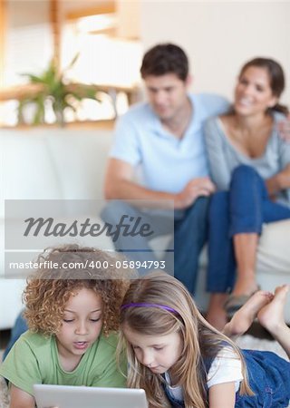 Portrait of children using a tablet computer while their parents are watching in their living room