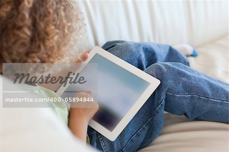 Back view young boy using a tablet computer in a living room