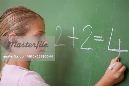 Schoolgirl writing a number on a blackboard