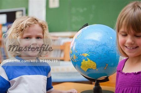Young pupils posing in front of a globe in a classroom