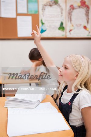 Portrait of a pupil raising her hand in a classroom