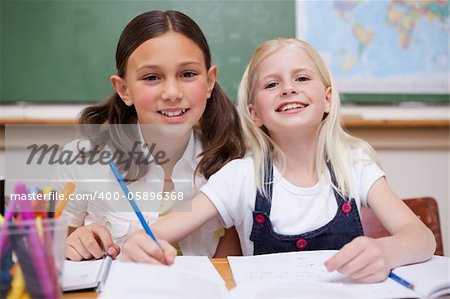 Smiling pupils working together on an assignment in a classroom