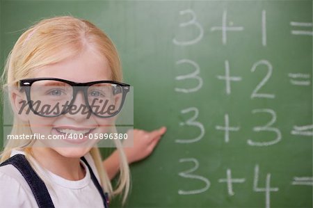 Smart schoolgirl pointing at something on a blackboard