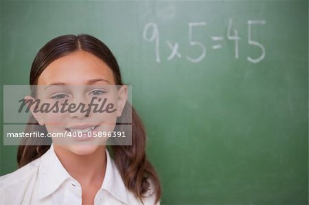 Smiling schoolgirl posing in front of a chalkboard in a classroom