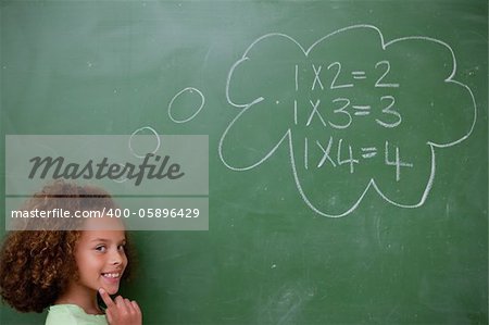 Schoolgirl thinking about mathematics in front of a blackboard