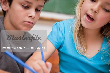 Close up of two children writing in a classroom
