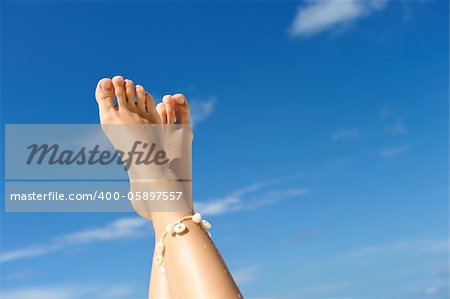 Women's beautiful legs on the beach against sky