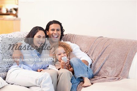 Happy young family watching television together