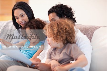 Happy young family on the sofa looking at photo album together