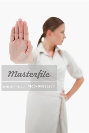 Portrait of a young businesswoman making a stop sign with the camera focus on her hand