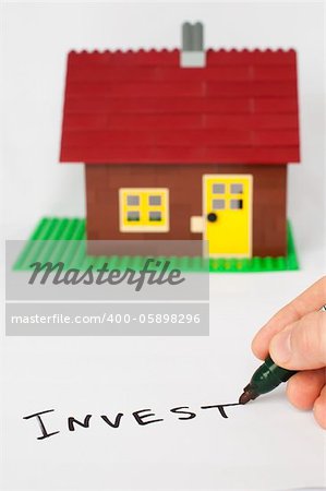 Hand write text Invest and house on background.