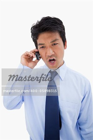 Portrait of an angry businessman making a phone call against a white background