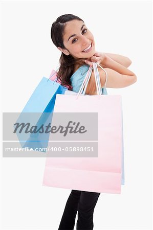 Portrait of a smiling woman posing with shopping bags against a white background