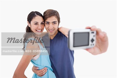 Young couple taking a picture of themselves against a white background