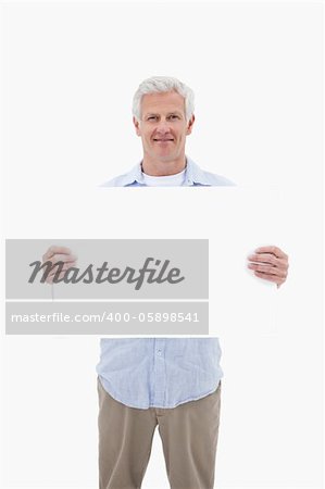 Portrait of a mature man holding a blank panel against a white background