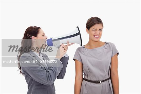 Businesswoman with megaphone yelling at colleague against a white background