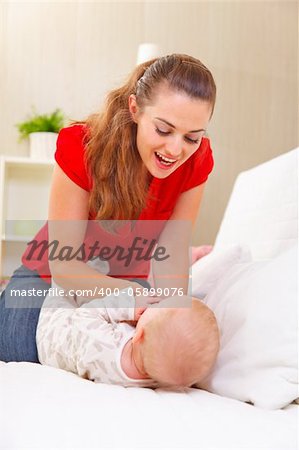 Young mother playing with baby on divan