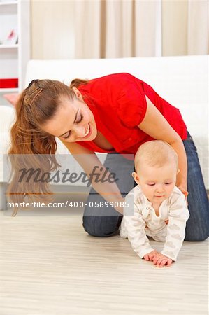 Mother helping cheerful baby learn to creep