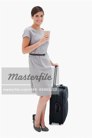 Smiling woman with coffee and wheely bag against a white background
