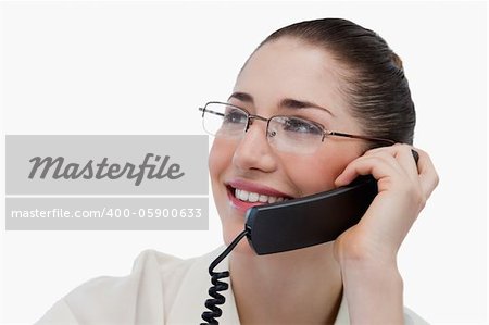 Close up of a smiling secretary making a phone call against a white background