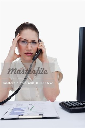 Portrait of a tired manager making a phone call while looking at statistics against a white background