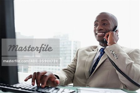 Businessman on the phone while using a computer in his office