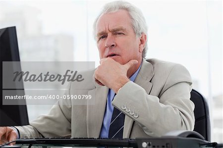 Thoughtful senior manager working with a monitor in his office