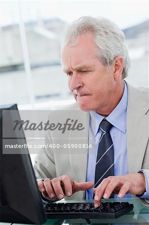 Portrait of a serious senior manager using a computer in his office