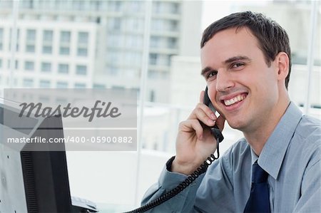 Happy office worker on the phone in his office