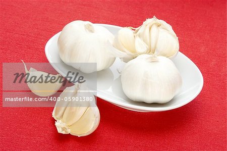 garlic in white bowl over red fabric background