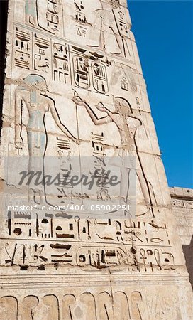 Egyptian hieroglyphic carvings and paintings on wall of the ancient temple at Medinat Habu in Luxor