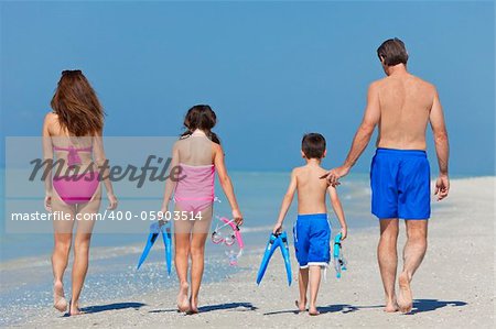 A happy family of mother, father and child, a daughter, walking in swimming costumes on a sunny beach