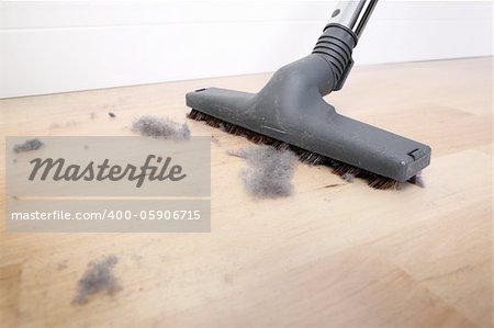 A picture of a vacuum cleaning wooden floor covered with dust