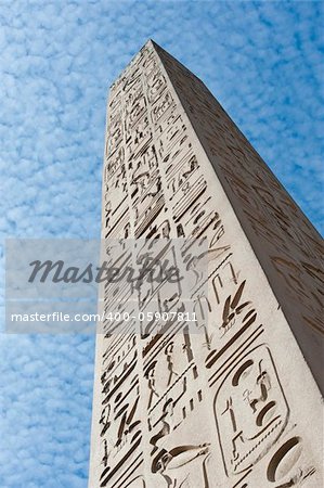 Large ancient obelisk with egyptian hieroglyphics at Karnak temple in Luxor against a blue sky background