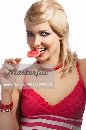 Young pretty girl with color make up hairstyle and color dress drinking from colored bottle some drink, she looks in to the lens, smiles and eats lollipop