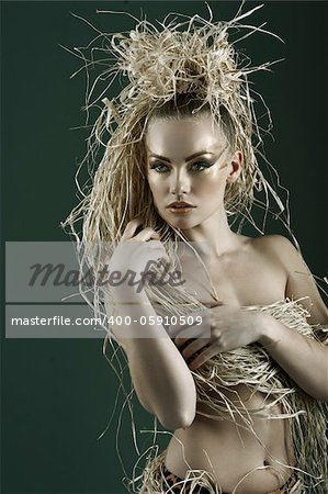 beautiful and sexy woman with raffia hair and a ethnic costume in a shot over dark with creative  gold make up