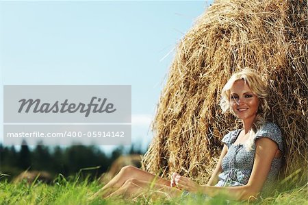 portrait of a girl next to a stack of hay under the blue sky