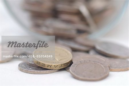 Spilled Coins from Glass Jar, focus on £1 coin. Sterling.