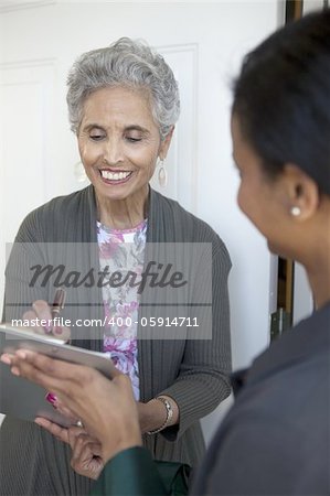 Black senior woman signs a petition at her front door