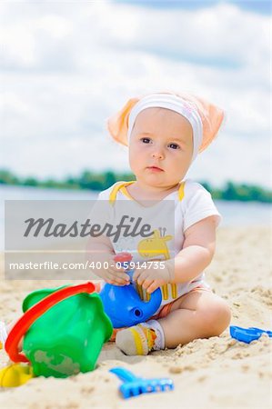 cute baby girl playing on the beach with sand. Vertical view