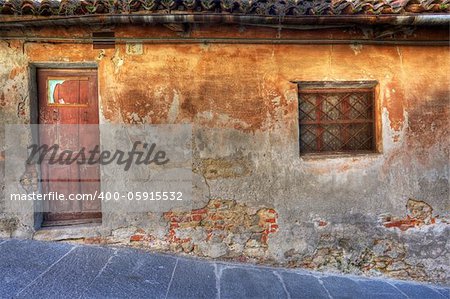 Old vintage abandoned house with small window and wooden door in town of La Morra, Northern Italy.