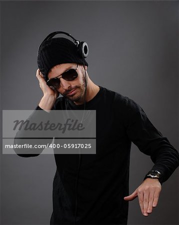 DJ listening to headphones on a dark background.  His hand is out as he is about to spin a record.