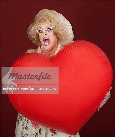 Emotional drag queen holds large red heart
