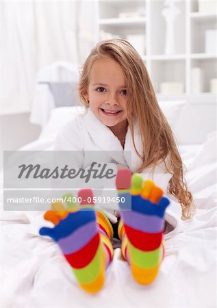 Happy little girl after bath wearing bathrobe and colorful sock