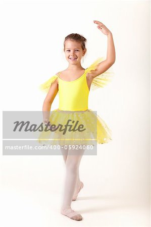 Smiling little ballerina exercising, studio shot on white background