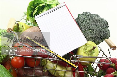 Basket with fresh vegetables, shopping list and pencil