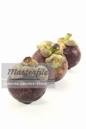 three mangosteen fruits on a light background