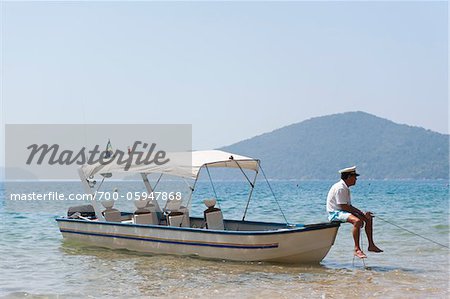 Homme assis sur un bateau, près de Paraty, Rio de Janeiro, Brésil