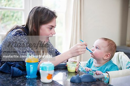 Girl feeding baby brother at table