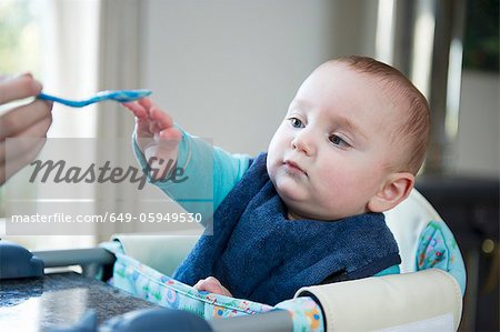 Baby reaching for spoon at table